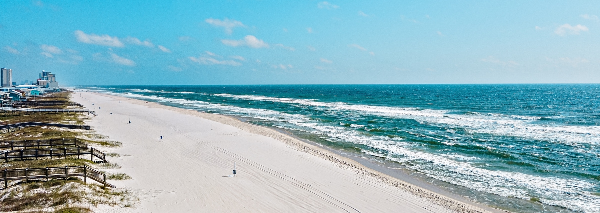 Aerial view of white sand beach, dune boardwalks and Gulf surf along Gulf Shores, Alabama