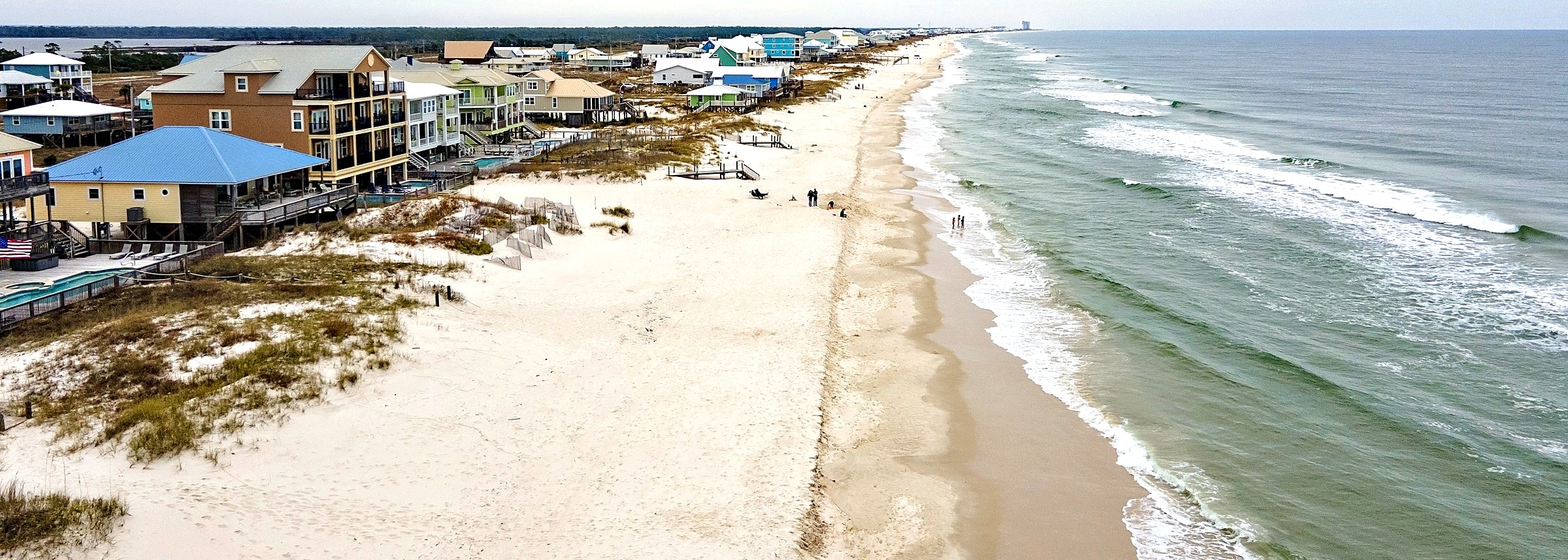 Aerial view of beach houses, white sand and Gulf surf along the beach in Fort Morgan, Alabama