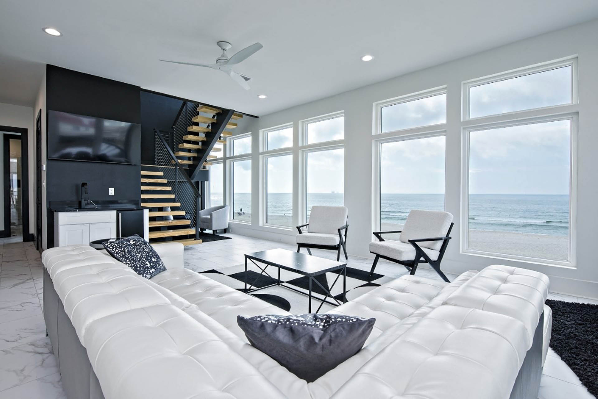 Living room with white sectional sofa and large windows facing the Gulf