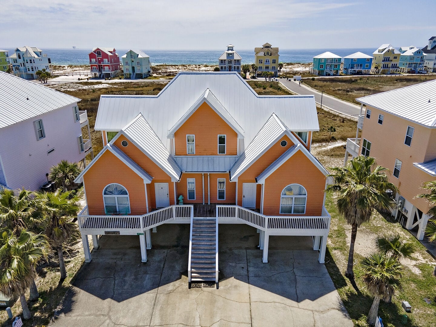 Orange beach house with palm trees at Mai Tai West in Fort Morgan, Alabama