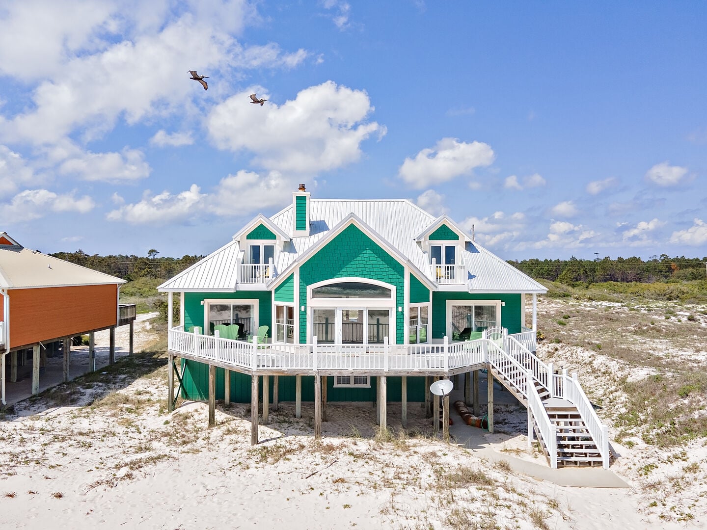 Green beach house with wraparound deck at Peace of Mind in Fort Morgan, Alabama