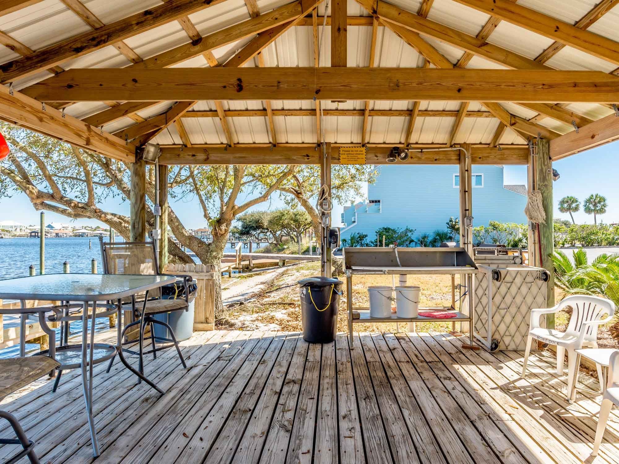 Covered deck with table and chairs by the water at Shipwatch in Perdido Key, Florida